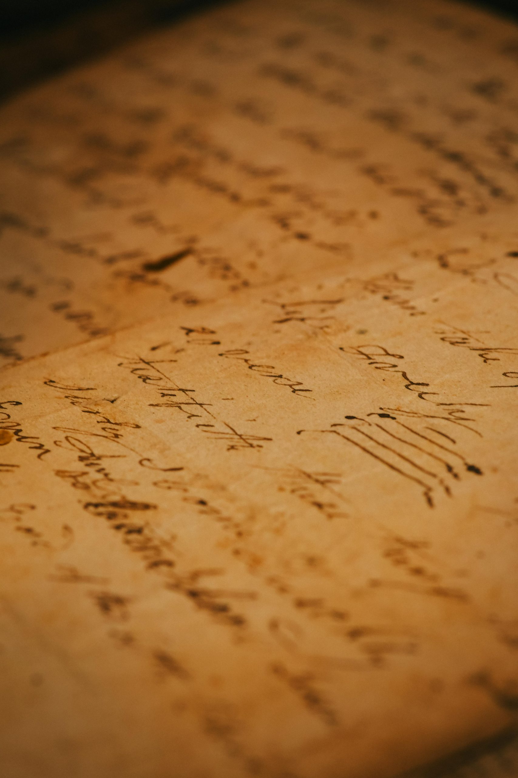 Close-up of an antique handwritten document with cursive writing on aged paper.