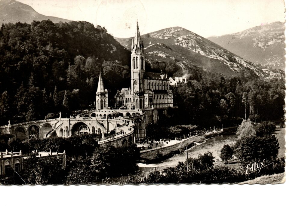 Carte postale ancienne de Lourdes montrant la basilique et les montagnes en 1957